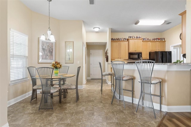 kitchen with light brown cabinets, baseboards, hanging light fixtures, light countertops, and black appliances