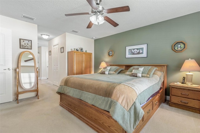 bedroom with light colored carpet, visible vents, and a textured ceiling