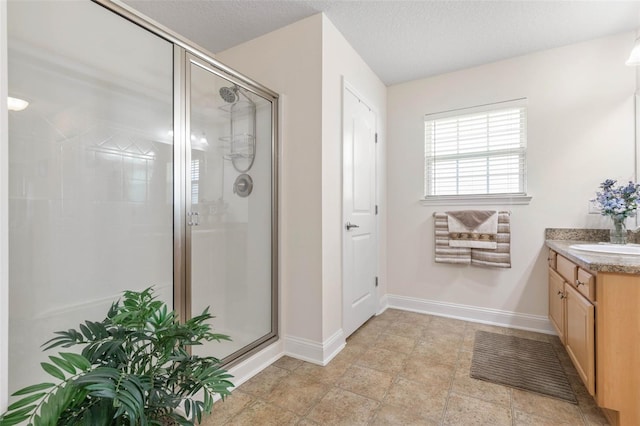 full bathroom with a shower stall, baseboards, a textured ceiling, and vanity