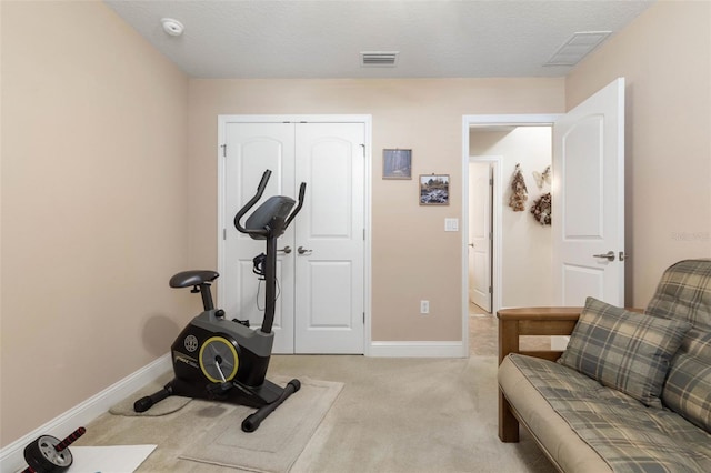 workout area featuring light carpet, visible vents, and baseboards