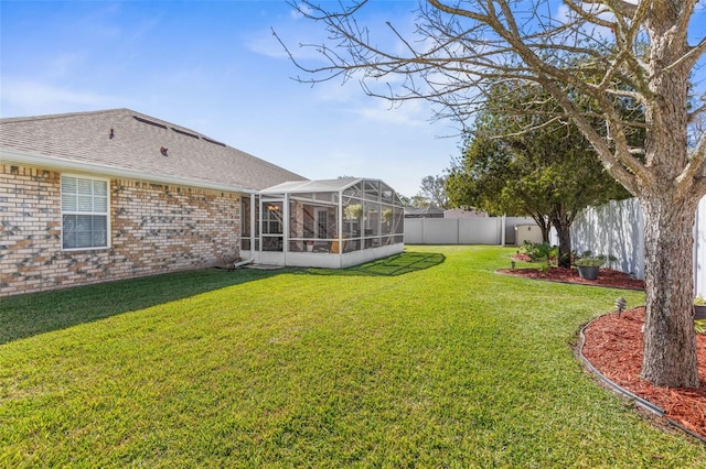 view of yard with glass enclosure and a fenced backyard