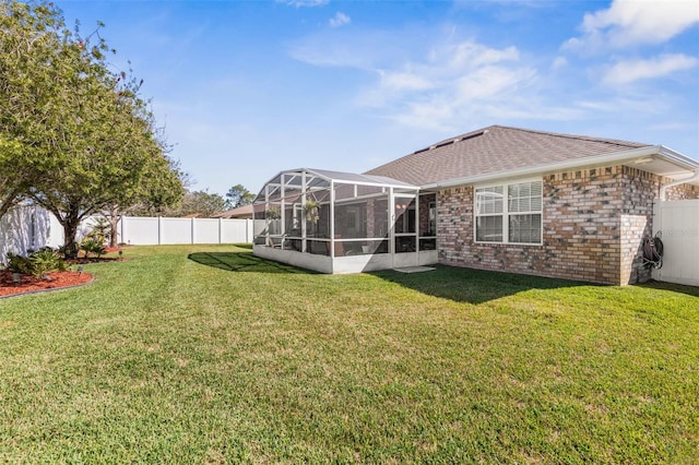 view of yard with glass enclosure and a fenced backyard