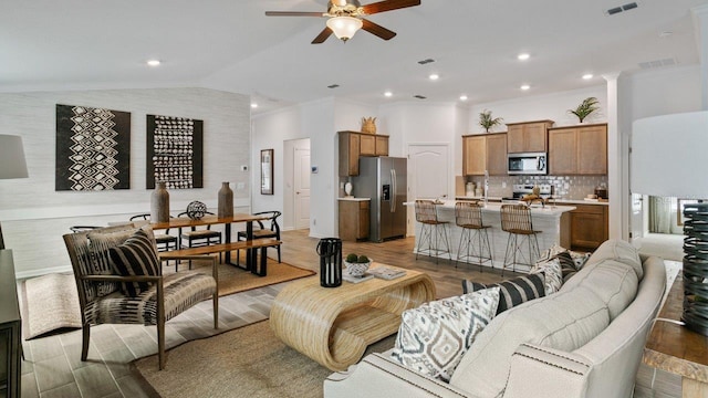 living room featuring crown molding, lofted ceiling, wood-type flooring, and ceiling fan