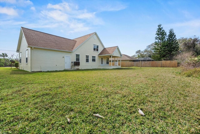 rear view of house featuring cooling unit and a lawn