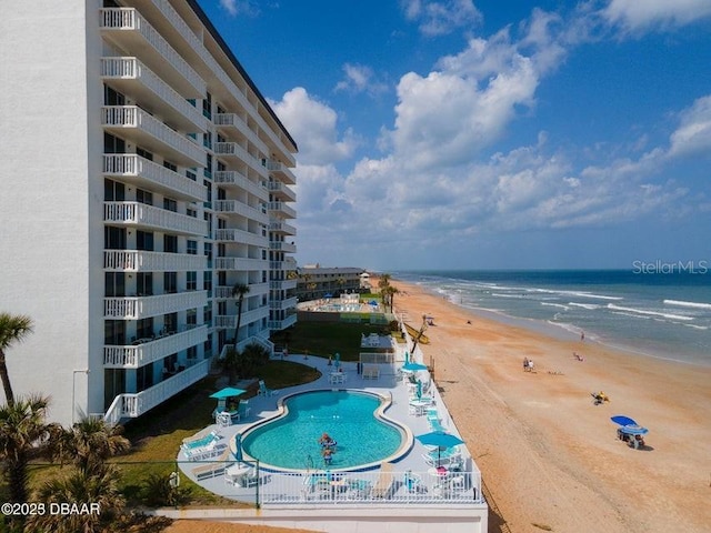 view of swimming pool with a patio, a beach view, and a water view