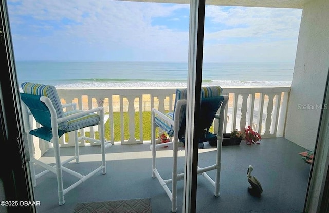 balcony with a water view and a view of the beach