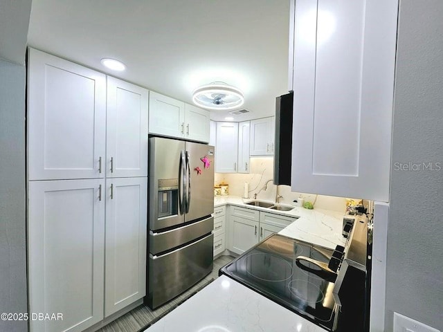 kitchen featuring stainless steel appliances, sink, white cabinets, and light stone counters