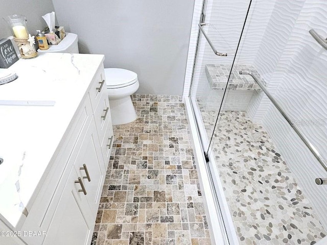 bathroom featuring vanity, a shower with shower door, and toilet