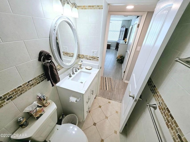 bathroom with vanity, tile walls, tile patterned floors, and toilet