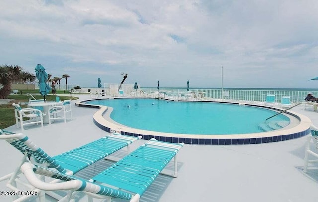 view of swimming pool with a patio area and a water view