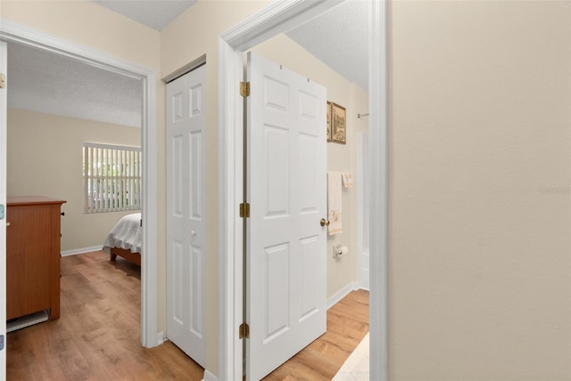 hallway featuring a textured ceiling and light hardwood / wood-style flooring