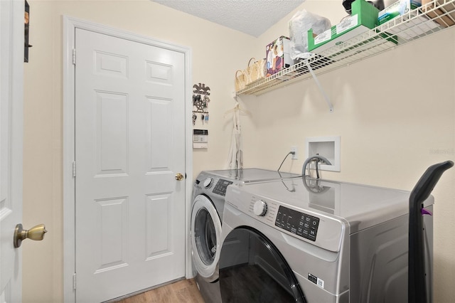 washroom with light wood-type flooring, washer and dryer, and a textured ceiling