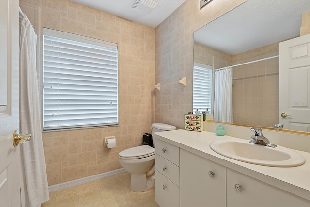 bathroom featuring vanity, tile walls, and toilet