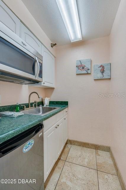 kitchen with stainless steel appliances, sink, a textured ceiling, and white cabinets