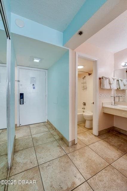 corridor with light tile patterned floors and a textured ceiling