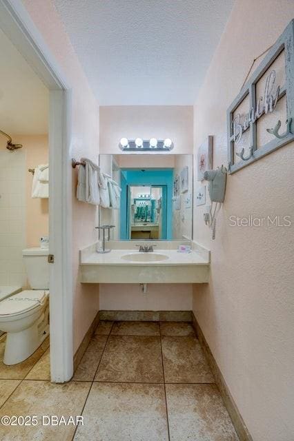 bathroom with toilet, tile patterned flooring, sink, and a textured ceiling