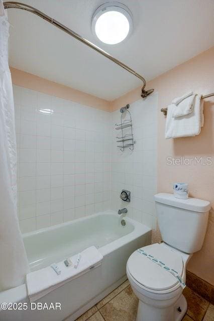 bathroom featuring tile patterned flooring, shower / bath combination with curtain, and toilet