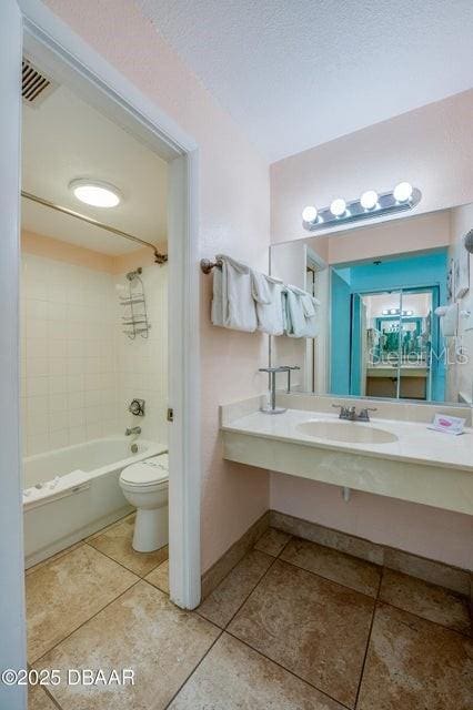 full bathroom with tile patterned floors, toilet, sink, a textured ceiling, and tiled shower / bath combo