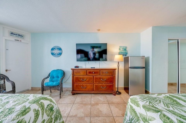 tiled bedroom featuring stainless steel refrigerator, a closet, and a textured ceiling