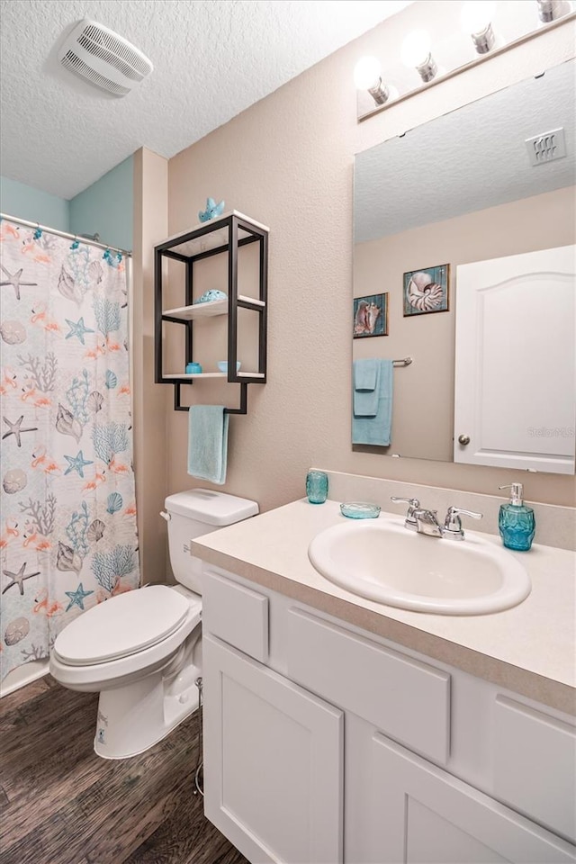 bathroom with hardwood / wood-style floors, vanity, a textured ceiling, toilet, and walk in shower