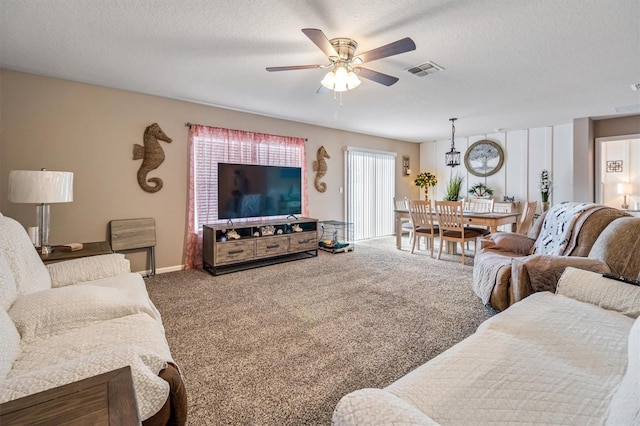 living room featuring ceiling fan, carpet, and a textured ceiling