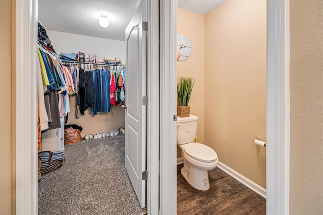 bathroom with hardwood / wood-style floors, toilet, and a textured ceiling