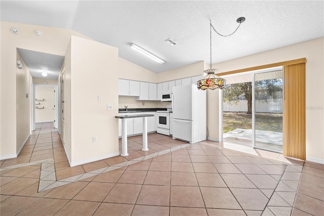 kitchen featuring lofted ceiling, hanging light fixtures, light tile patterned floors, white appliances, and white cabinets