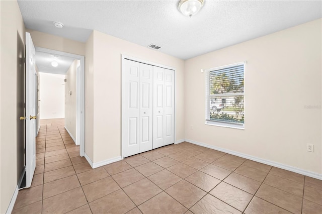 unfurnished bedroom with light tile patterned floors, a closet, and a textured ceiling