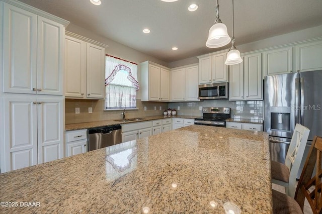 kitchen featuring a breakfast bar, sink, white cabinetry, decorative light fixtures, and appliances with stainless steel finishes