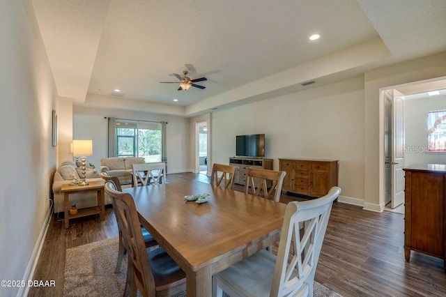 dining room featuring ceiling fan, dark hardwood / wood-style floors, and a raised ceiling