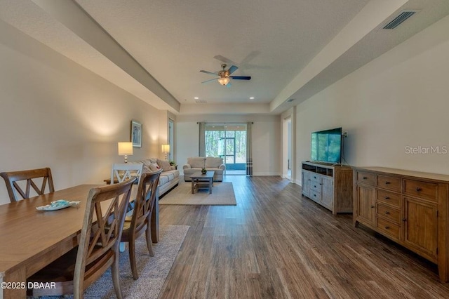 dining area featuring ceiling fan, a tray ceiling, and hardwood / wood-style floors