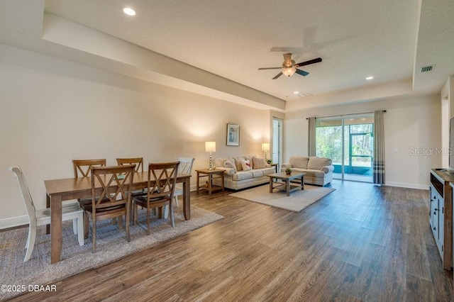 dining room featuring hardwood / wood-style floors, a raised ceiling, and ceiling fan