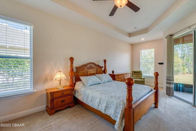 bedroom featuring ceiling fan, light colored carpet, a tray ceiling, and access to exterior