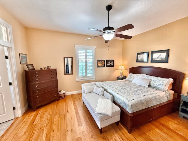 bedroom with light wood-type flooring, a ceiling fan, and baseboards