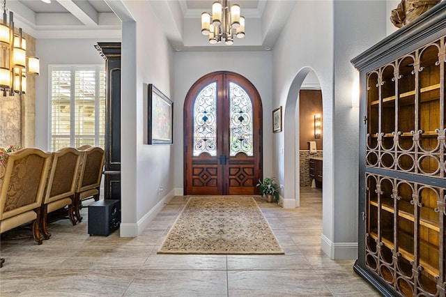 foyer featuring crown molding, a notable chandelier, and french doors