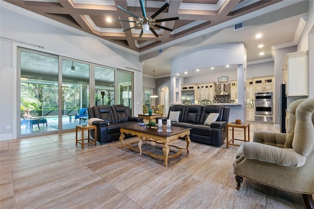 living room with a high ceiling, crown molding, coffered ceiling, and ceiling fan