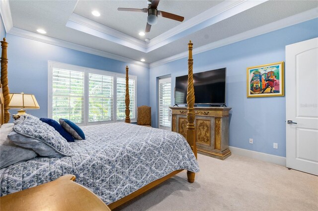 carpeted bedroom featuring crown molding, ceiling fan, and a tray ceiling