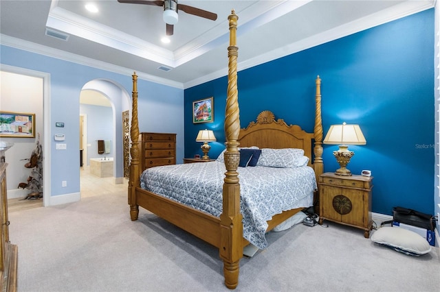 bedroom with ensuite bathroom, crown molding, a tray ceiling, carpet flooring, and ceiling fan