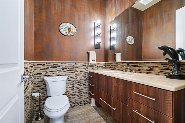 bathroom with vanity, toilet, and tile walls