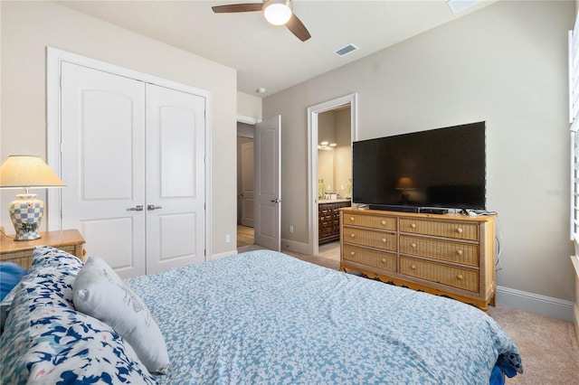 bedroom featuring ensuite bath, light colored carpet, ceiling fan, and a closet