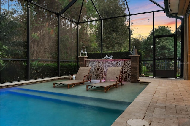 pool at dusk with a lanai and a patio