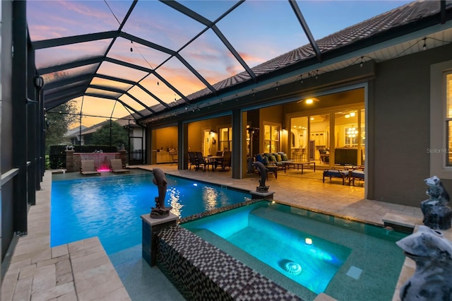 pool at dusk with area for grilling, glass enclosure, outdoor lounge area, an in ground hot tub, and a patio