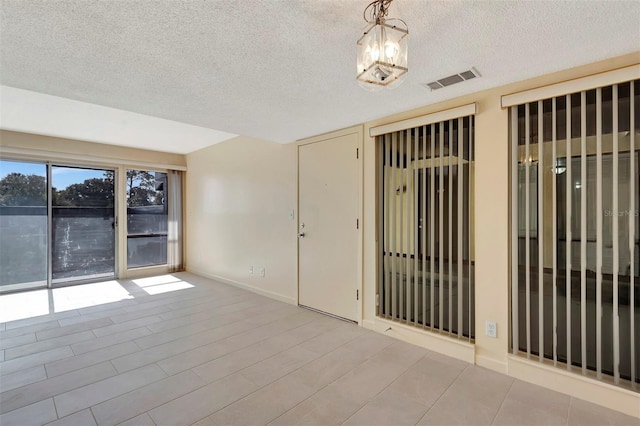 48 Club House Dr Unit 106, Palm Coast, FL 32137 - empty room with an inviting chandelier, baseboards, a textured ceiling, visible vents, and wood finished floors
