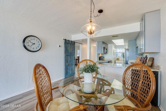 dining area featuring hardwood / wood-style flooring, a barn door, and a textured ceiling