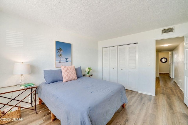 bedroom featuring light hardwood / wood-style floors, a closet, and a textured ceiling