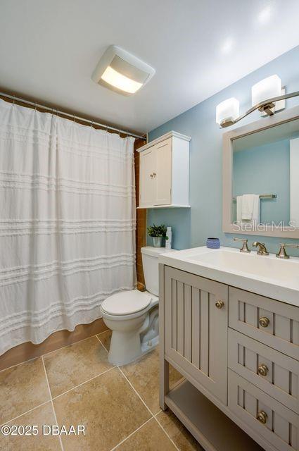 bathroom with walk in shower, vanity, toilet, and tile patterned flooring