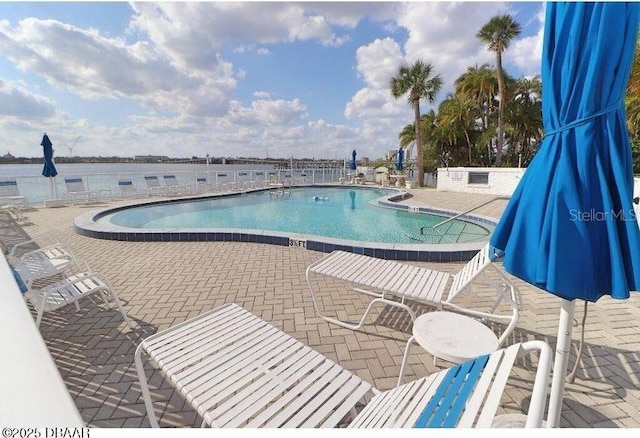 view of pool featuring a water view and a patio area