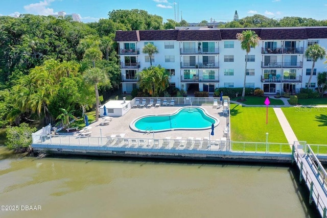 view of swimming pool featuring a water view, a patio, and a lawn