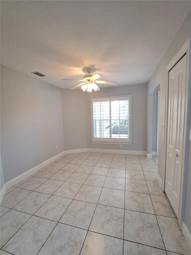 unfurnished room with ceiling fan, a textured ceiling, and light tile patterned floors