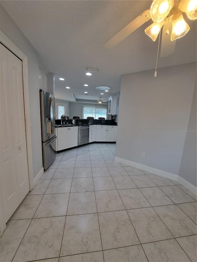 kitchen with sink, light tile patterned floors, ceiling fan, white cabinetry, and stainless steel appliances